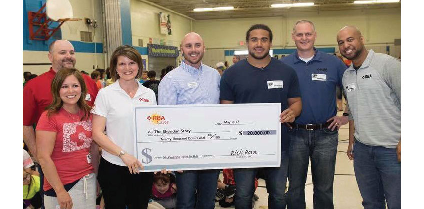 RBA employees donating check to Sheridan Story with Minnesota Vikings football player